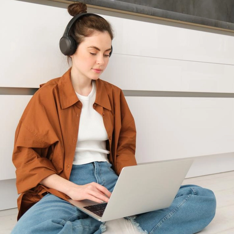 Frau sitz mit Laptop am Boden in der Küche. 